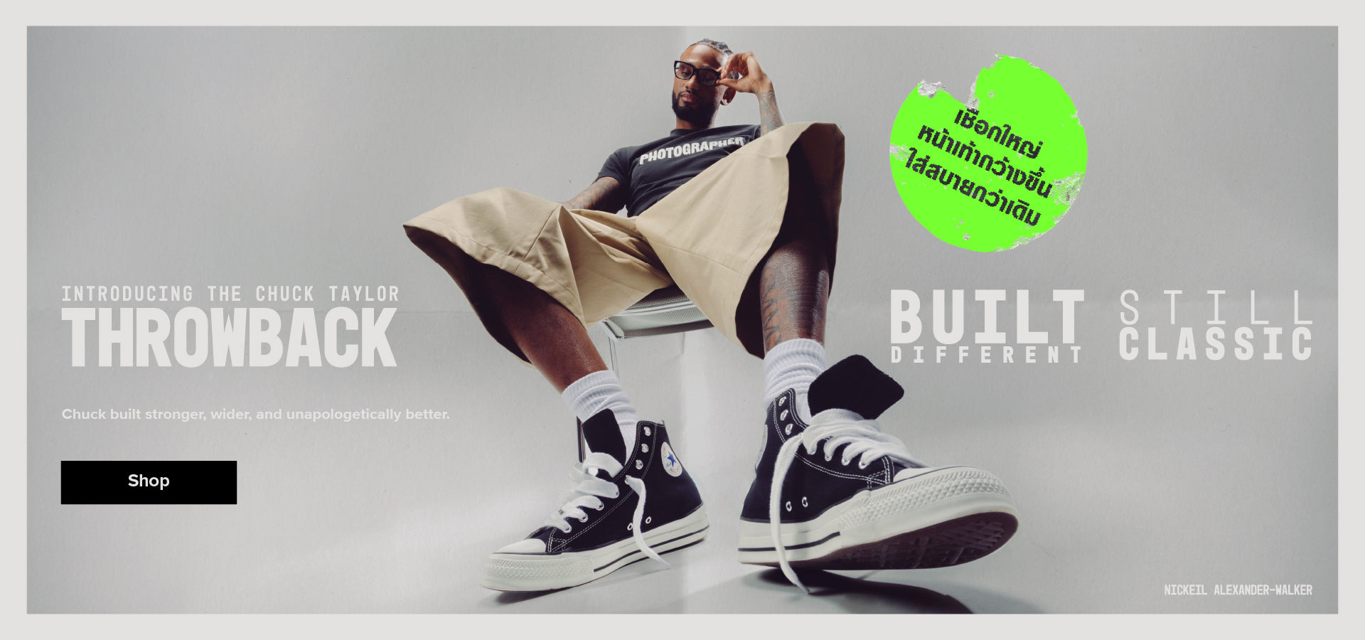Person sitting with Converse shoes on a gray background, featuring brand text and logo.